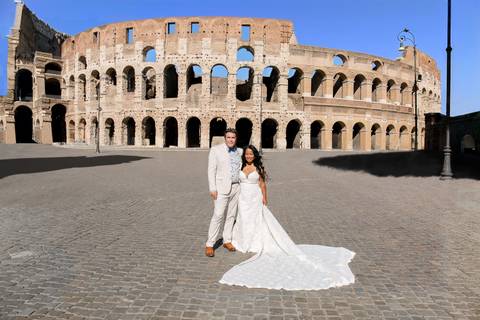 Bride and groom posing in front of the ancient Colosseum on sunny day.