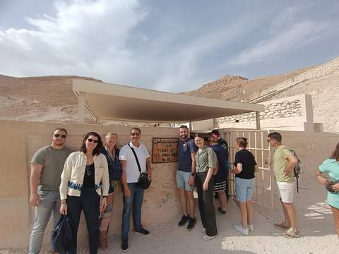 Tour group stands at the entrance sign of Tutankhamun’s tomb in the Valley of the Kings.