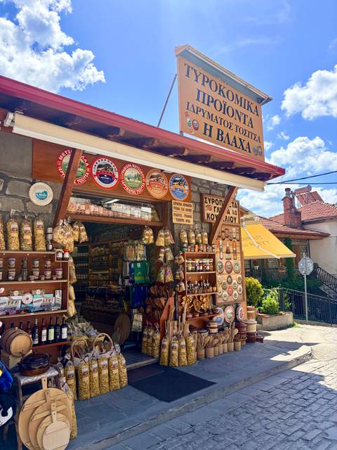 A colorful local delicatessen packed with spices, pasta, and souvenirs lines a village street.
