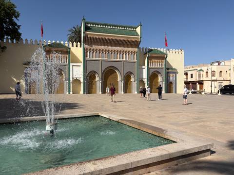 Fountain splashes in front of the ornate arched gates of the Royal Palace in Meknes.