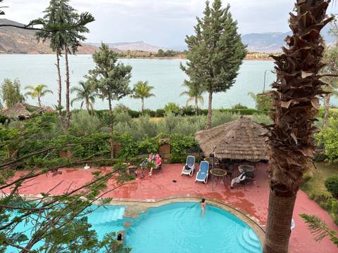 Resort pool and patio overlook a shimmering lake framed by palms and mountains.