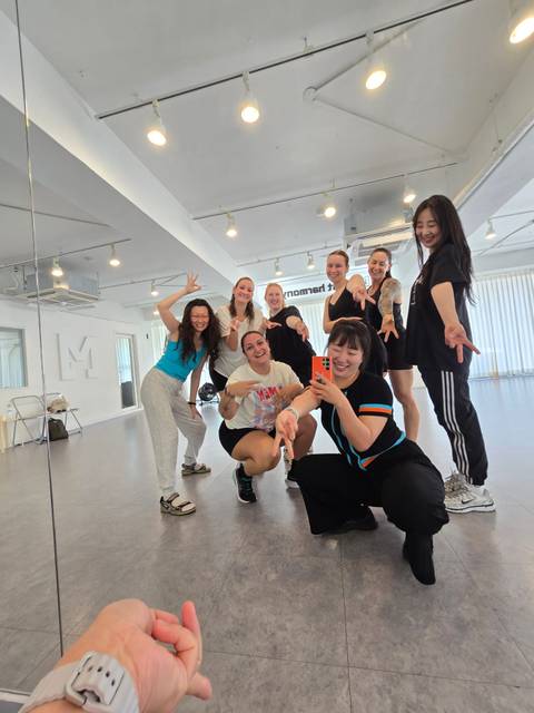 Dance class participants strike playful poses in a mirrored studio.