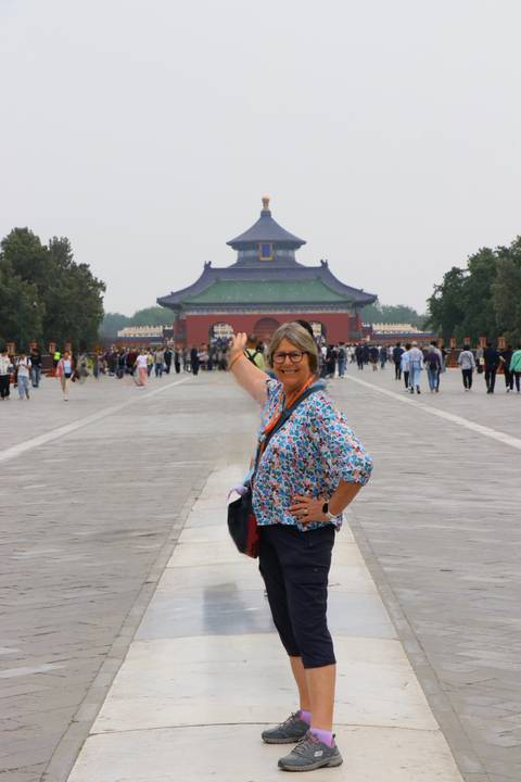 Traveler posing and pointing down the central axis toward the Hall of Prayer for Good Harvests at the Temple of Heaven complex.