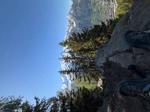 Relaxed hiker’s view with boots propped on a rock facing snow-covered alpine peaks.