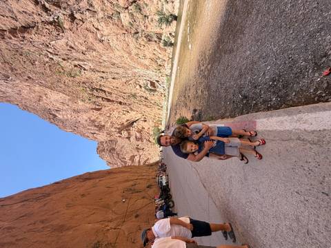 Father hugging two children on a road through a dramatic rocky gorge