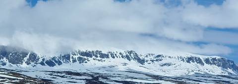 Snow-covered ridgeline half hidden by clouds in a wintry mountain landscape.
