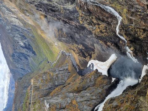Dramatic canyon with a tall waterfall plunging into a misty pool far below.