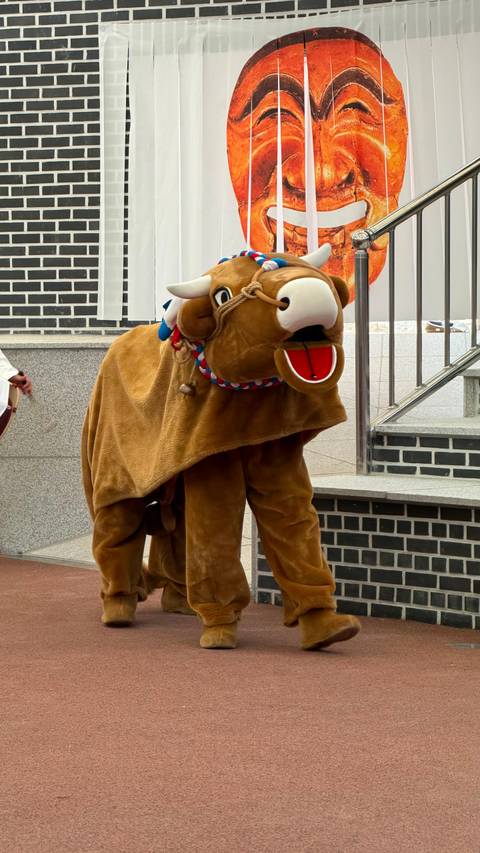 Person wearing an oversized brown animal costume with open mouth on an indoor stage