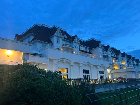 A modern hotel building illuminated at dusk beneath a deep blue evening sky.