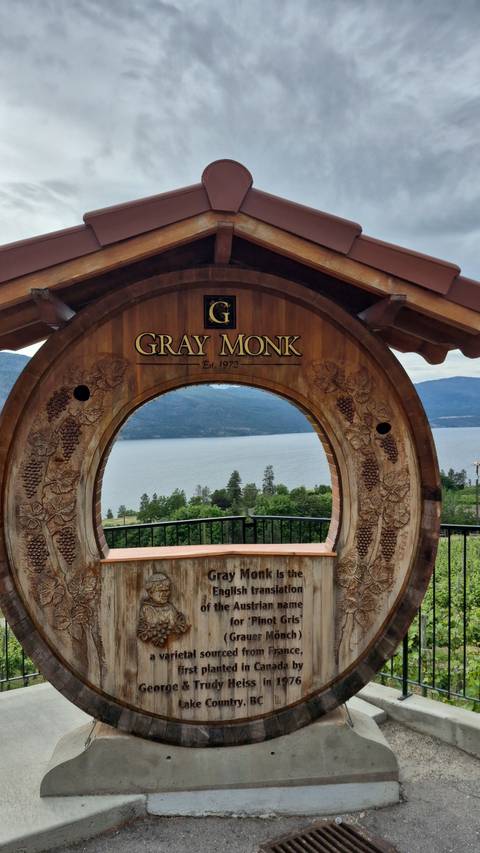 A carved wooden archway at Gray Monk winery overlooking Okanagan Lake and surrounding hills.