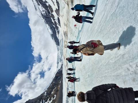 Visitors walking on the icy surface of the Athabasca Glacier surrounded by towering snowy peaks.