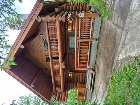 A rustic log cabin with flower baskets set among tall pine trees.