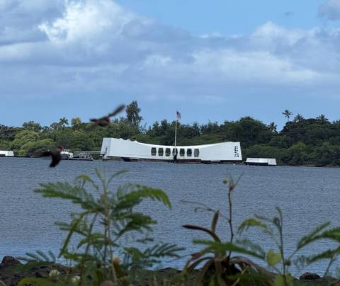 USS Arizona Memorial floating on the water at Pearl Harbor viewed from shore