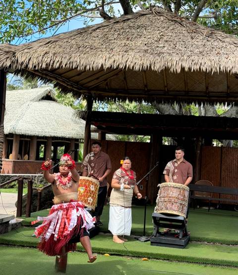 Musicians in traditional attire playing drums on an open-air stage
