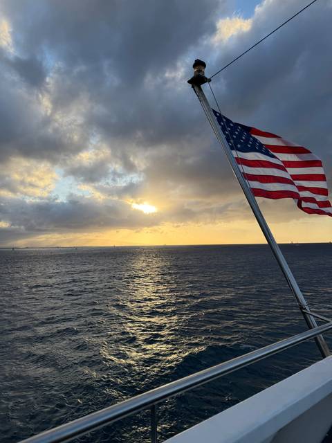 American flag on a boat with dramatic sunset over the ocean