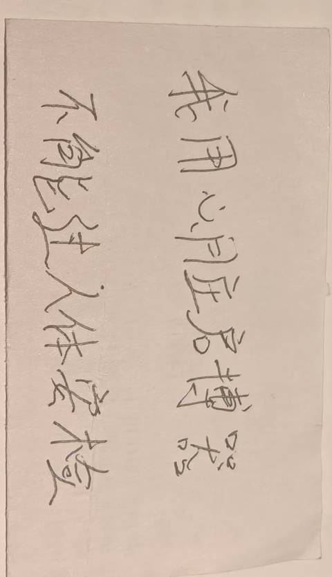 Handwritten Chinese calligraphy on a strip of paper