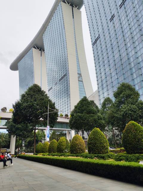 Modern glass towers of Marina Bay Sands complex with greenery in foreground