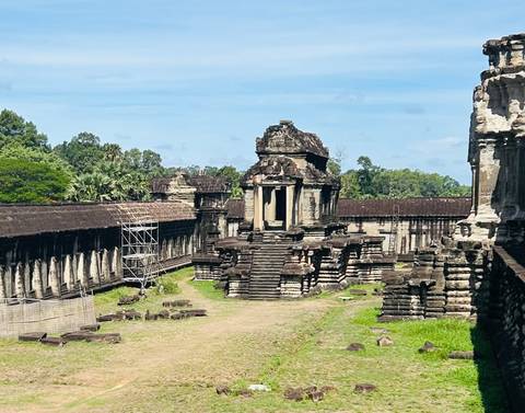 Stone corridors and central structure within the Angkor Wat temple complex under blue sky