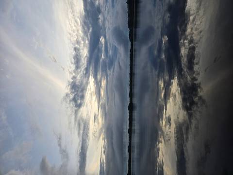 Moody twilight sky reflects on still rainforest lagoon waters creating mirror-like symmetry.