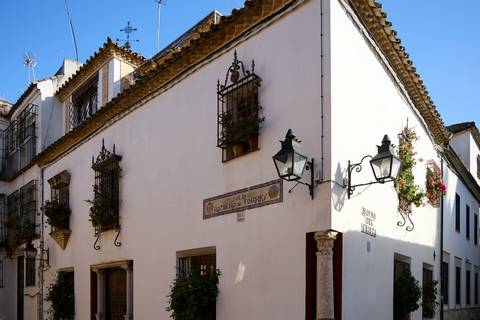 Corner view of a whitewashed Andalusian house adorned with wrought-iron balconies and flowers.