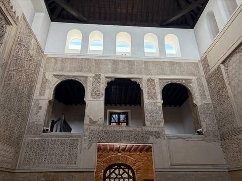Intricately carved Moorish interior with arched windows and geometric stucco.