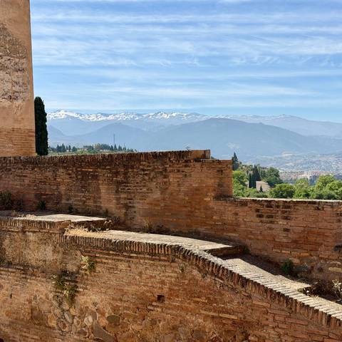Snow-capped Sierra Nevada mountains rise behind ancient brick walls.