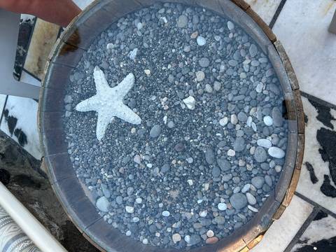 Decorative wooden basin filled with smooth pebbles and a starfish centerpiece.