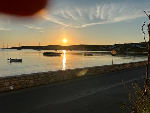 Low sun reflecting on a quiet bay beside a stone seawall and coastal road.