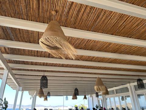 View looking up at a bamboo-covered ceiling with hanging woven lampshades.