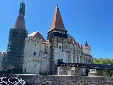 Medieval Corvin Castle with tall pointed towers, some sections under restoration scaffolding.