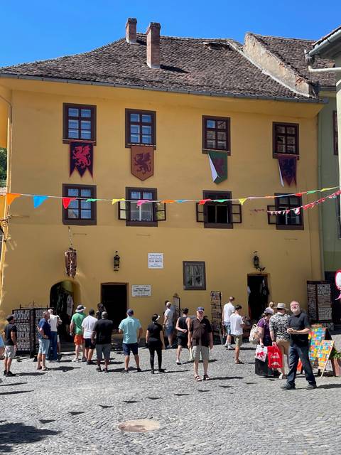 Crowds outside the mustard-yellow Vlad Dracul House decorated with medieval banners and bunting.
