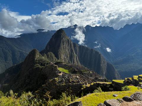 Iconic view of Machu Picchu citadel nestled among dramatic Andean peaks under patchy clouds.
