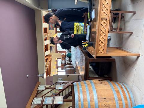 Guests gather in a cozy winery tasting room lined with barrels and glasses prepared for sampling.