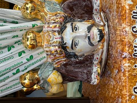 Decorative Sicilian ceramic head filled with gold-topped compostable straws on a market stall