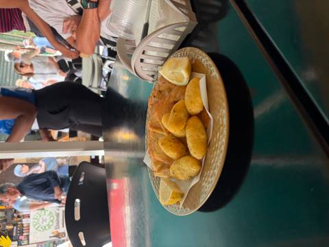 Fried potato croquettes and flatbread served with lemon on a busy café table as patrons mingle behind