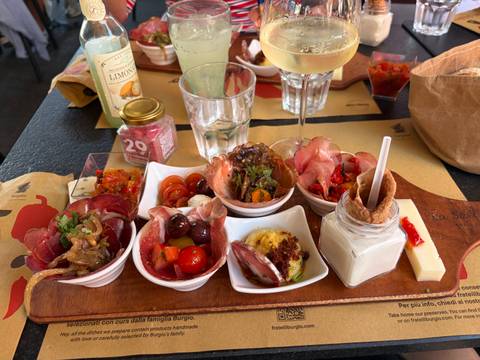 Wooden board loaded with assorted Sicilian antipasti, cheeses, cured meats and a glass of white wine