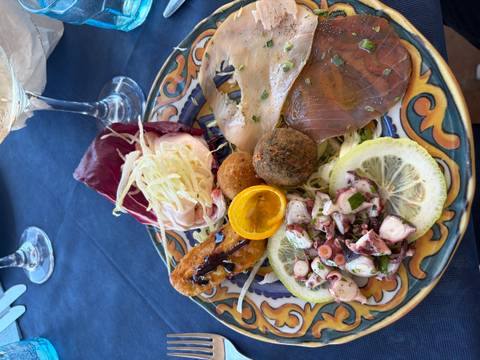 Colourful seafood antipasto plate with octopus salad, cured tuna and lemon slices on patterned ceramics