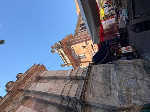 Upward view of ornate stone buildings and archways against a clear blue sky in a historic Sicilian town