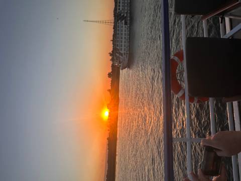 Vibrant sunset over the Nile River with a cruise boat passing by, viewed from a ship railing