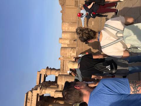 Tour group listening to a guide in front of the massive sandstone columns of Kom Ombo Temple