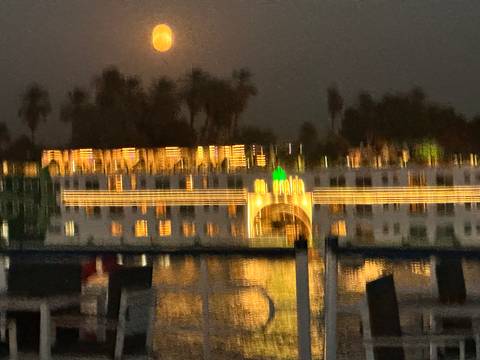 Blurry night view of an illuminated river cruise vessel reflecting on the water