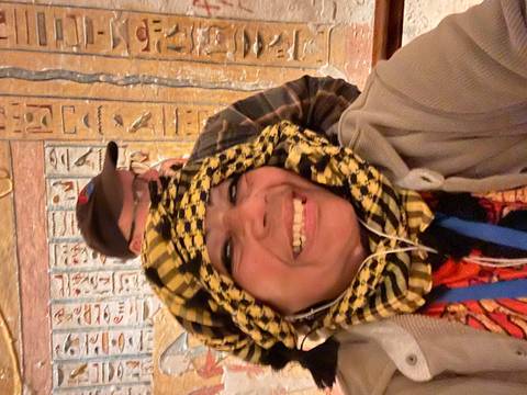 Smiling travellers taking a selfie inside a tomb covered with colorful hieroglyphs