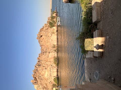 Rocky granite island formations rising from calm river waters beneath a clear sky