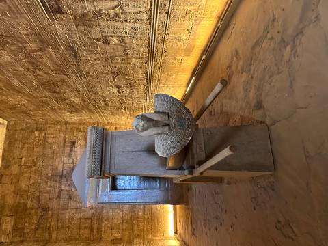 Sacred ceremonial barque shrine inside a dimly lit temple chamber with carved walls