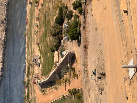 Desert landscape with excavation site, walls and Nile River visible from elevated viewpoint