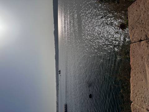 Glittering midday light across a broad lake or reservoir with hazy horizon