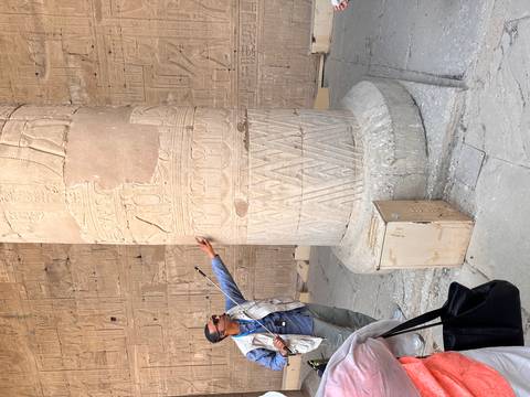 Guide points out detailed carvings on a massive temple column for visitors