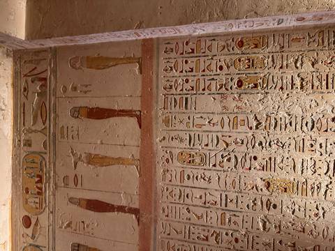 Wall covered in rows of colorful hieroglyphs and painted standing figures