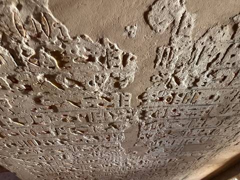 Eroded wall detail with deeply carved hieroglyphic symbols and traces of pigment