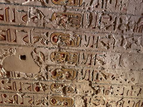 Vertical stone wall with rows of cartouches and hieroglyphs in varying states of preservation